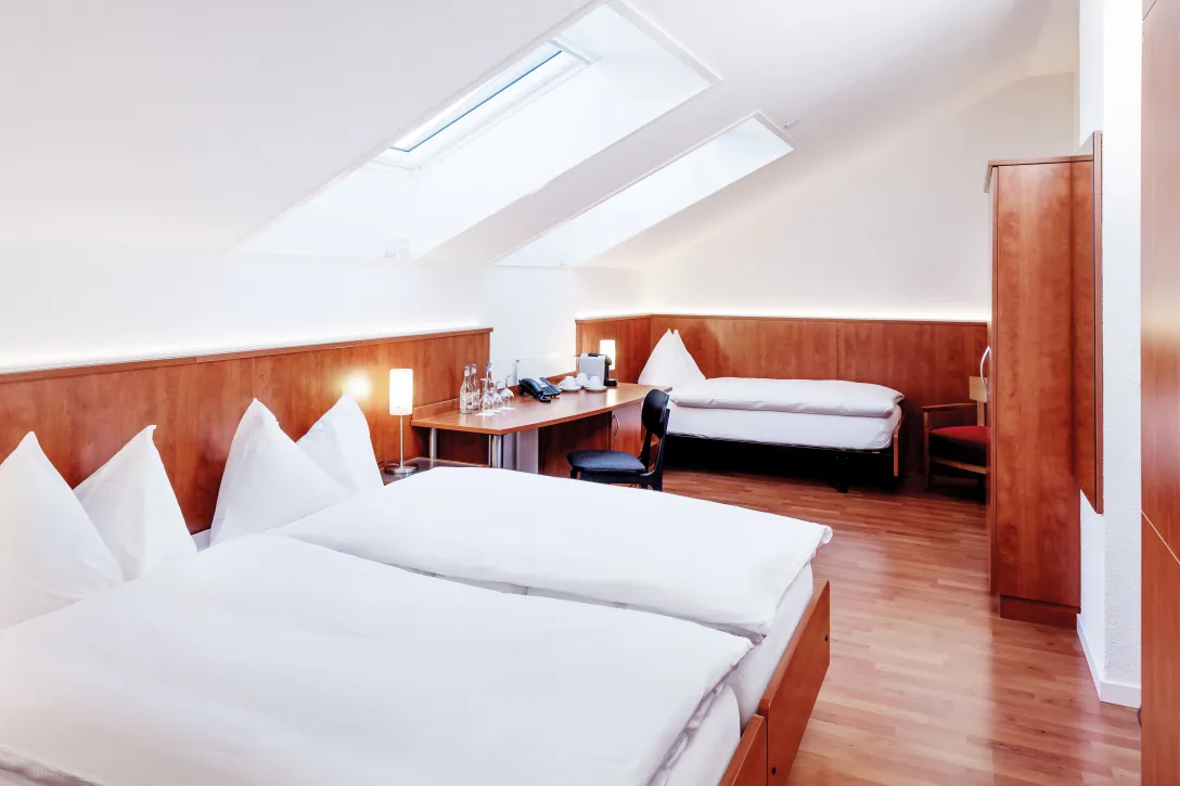 Sorell Hotel Sonnental Standard triple room with desk and wardrobe