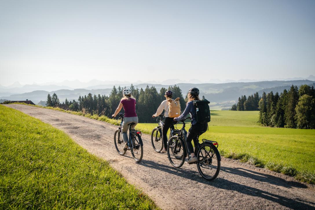 drei Personen fahren mit dem Velo durch die hügeligen Landschaften von Bern