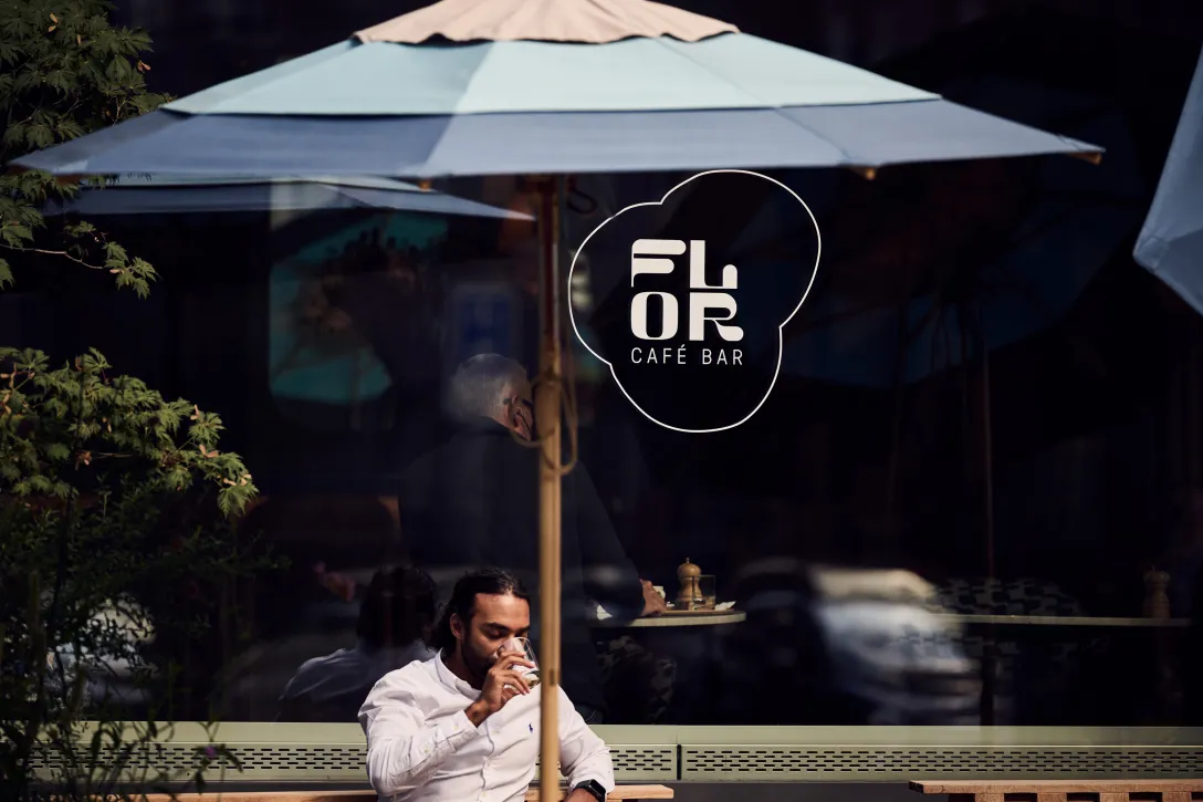 Mann sitz unter Sonnenschirm und trinkt einen Cocktail