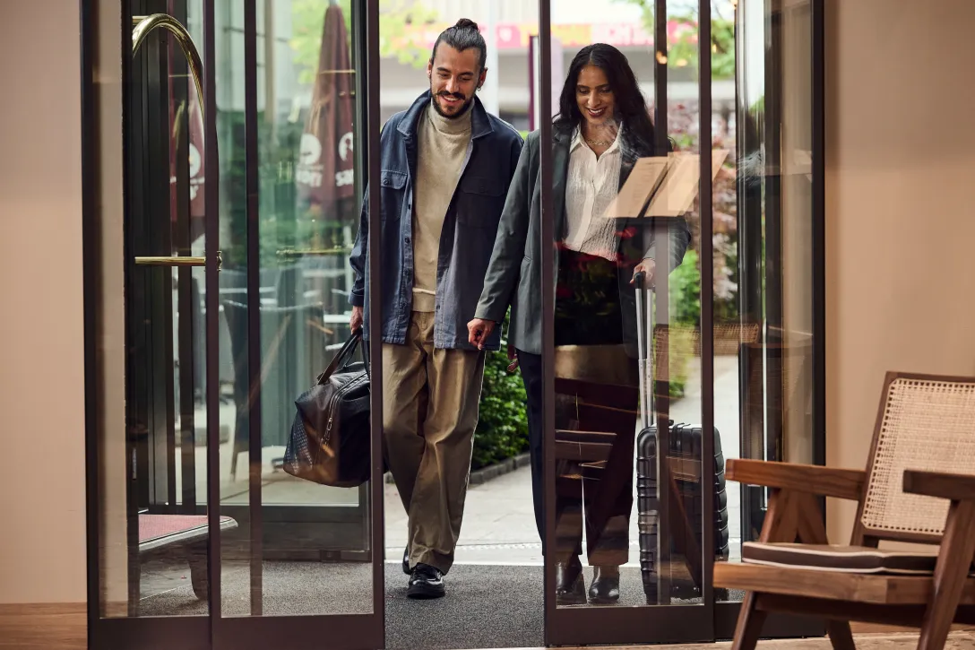 Paar reist im Hotel an und läuft durch die Eingangstüre