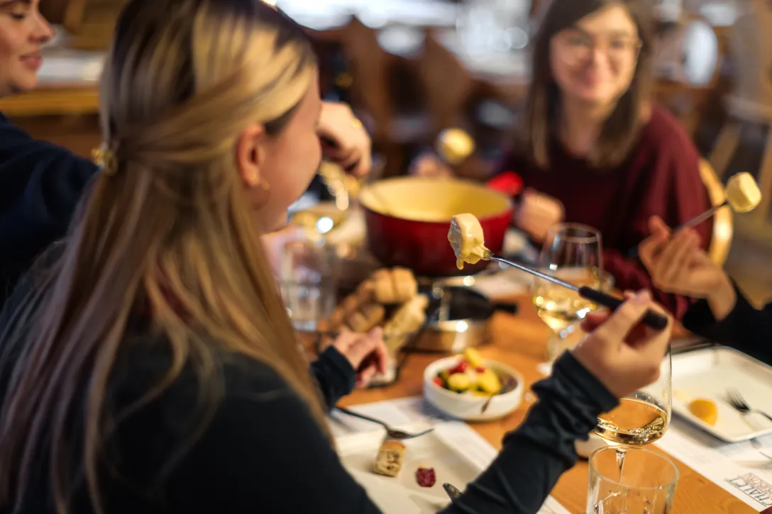 Frau isst Fondue in einem Chalet