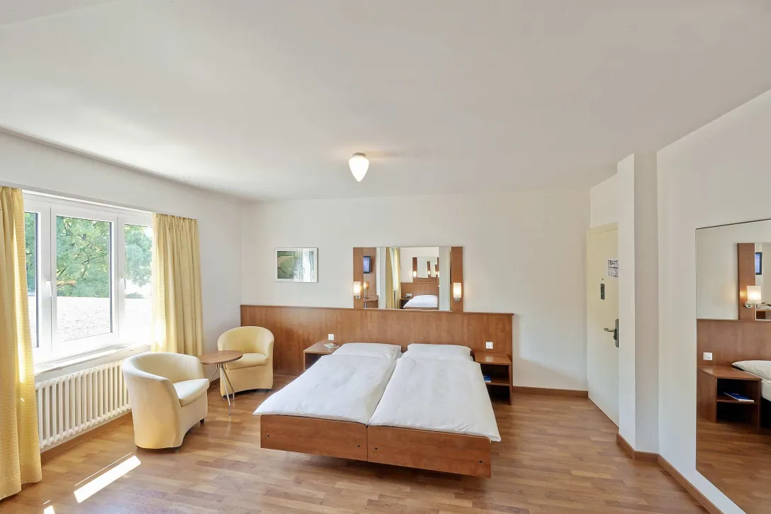 zwei Bett Zimmer mit Betten und zwei Sesseln
