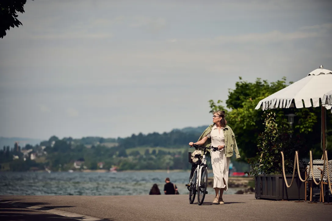 Frau läuft mit dem Fahrrad an der Promenade entlang
