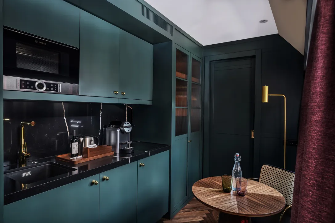 Hotelzimmer mit Küchenzeile, runden Tisch und modernen Schränken.
