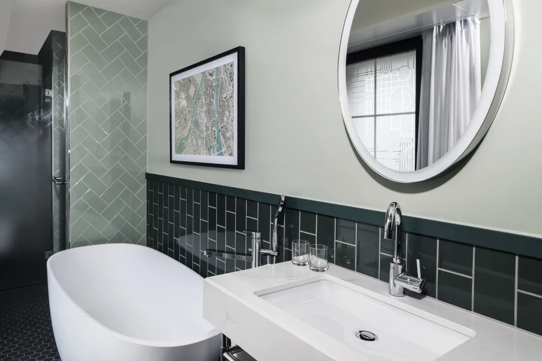 Modernes Badezimmer mit Badewanne, Waschbecken und rundem Spiegel.