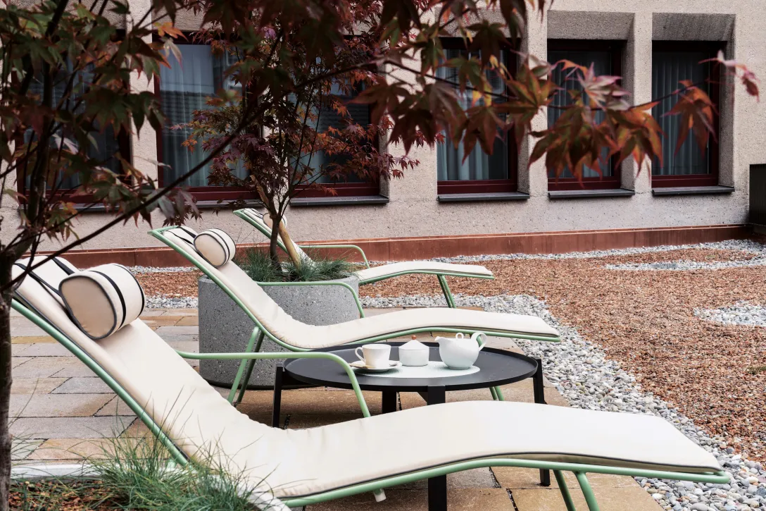 Liegestühle auf der Terrasse des Hotel mit Ahornbaum