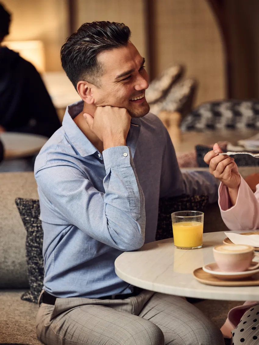 Mann sitzt am Tisch und trinkt Orangensaft