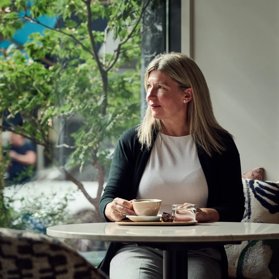 Frau sitzt am Tisch und trinkt Kaffee
