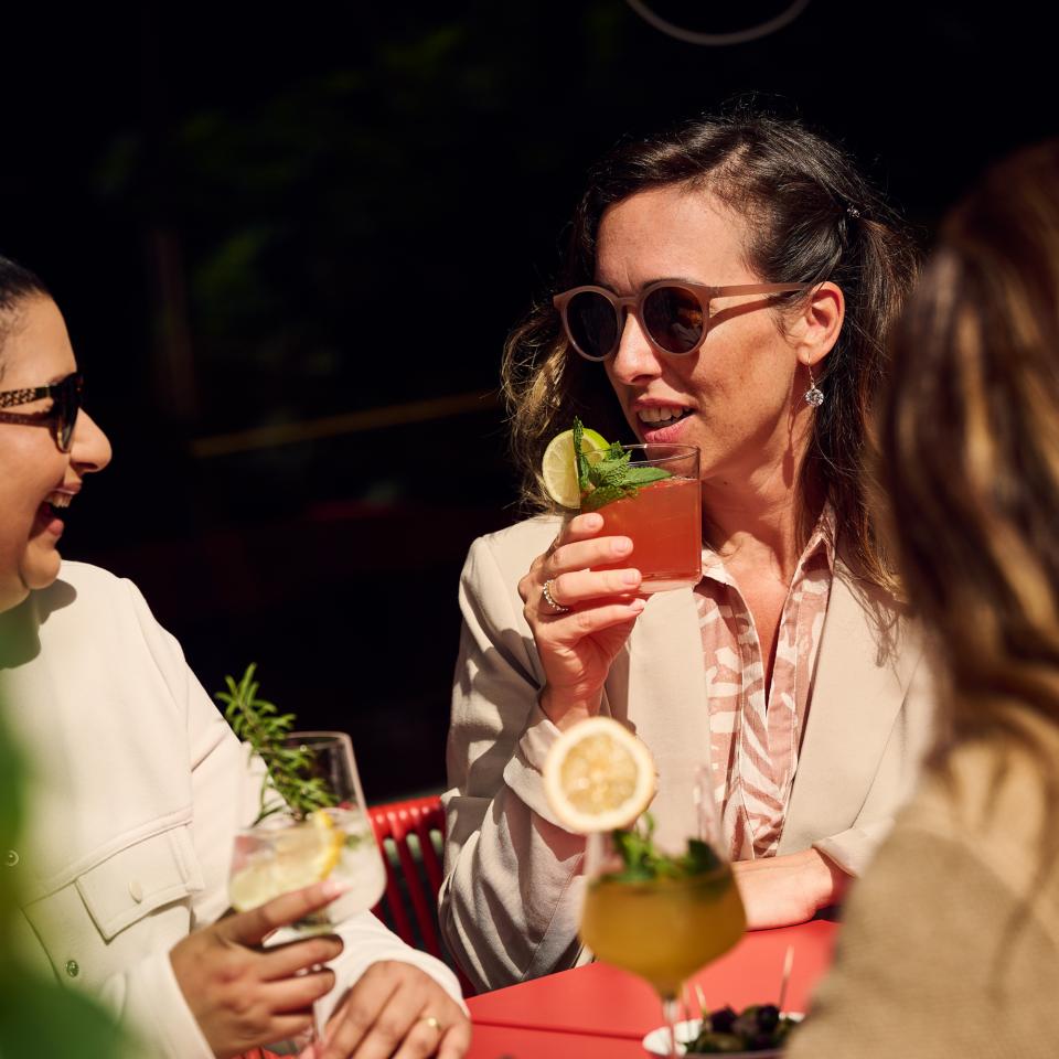 Frau trinke Cocktail auf der Terrasse in der Sonne