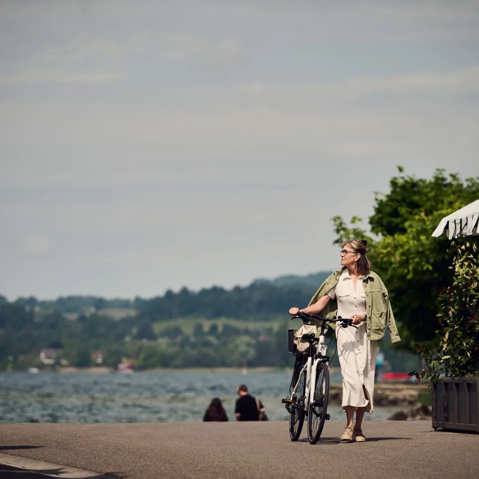 Frau läuft mit dem Fahrrad an der Promenade entlang