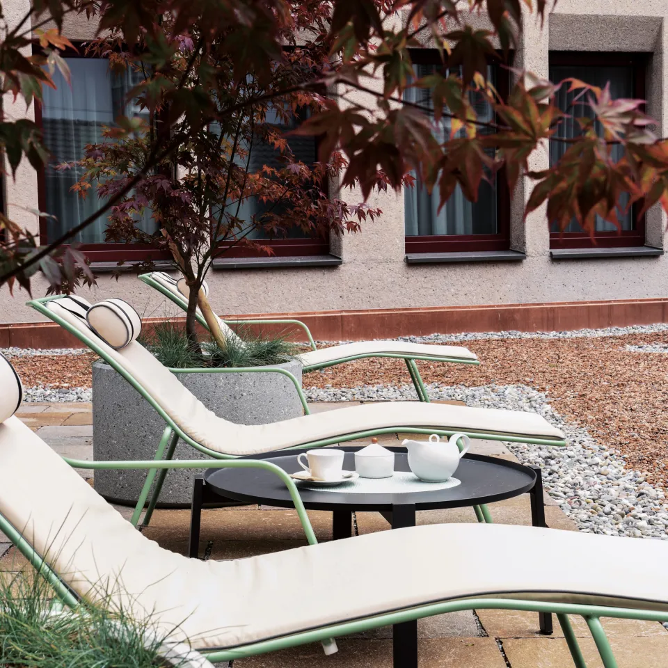 Liegestühle auf der Terrasse des Hotel mit Ahornbaum