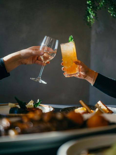 zwei Personen stossen mit Wein und Cocktail an