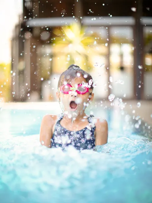 little girl with diving goggles in the swimming pool