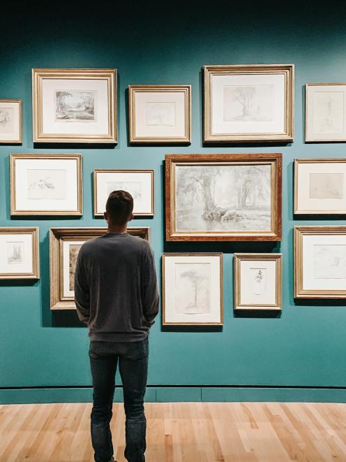 Mann steht vor einer Wand mit Bilder in einem Museum