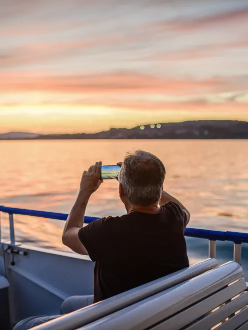 Man sits in a boat on Lake Zurich in the evening and takes a picture