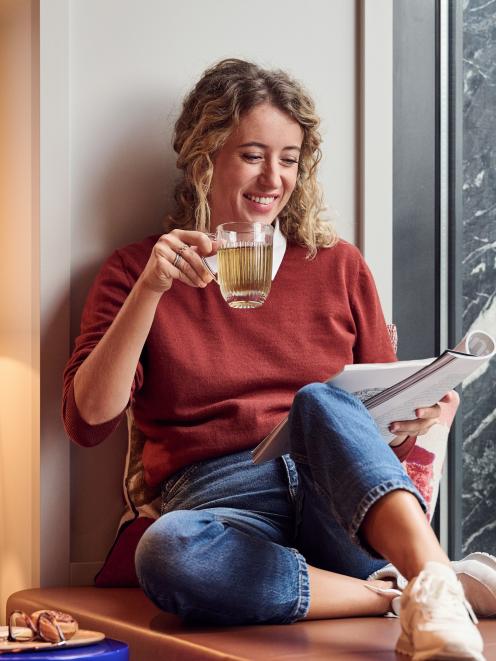 Frau sitzt am Fenster und trinkt Tee