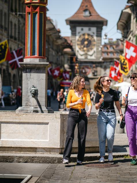 Drei Frauen laufen durch die Berner Altstadt und essen ein Glace