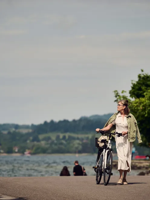 Frau läuft mit dem Fahrrad an der Promenade entlang