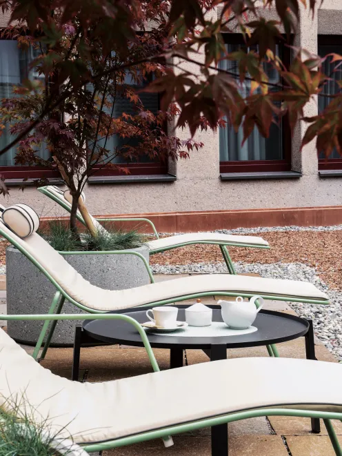 Liegestühle auf der Terrasse des Hotel mit Ahornbaum